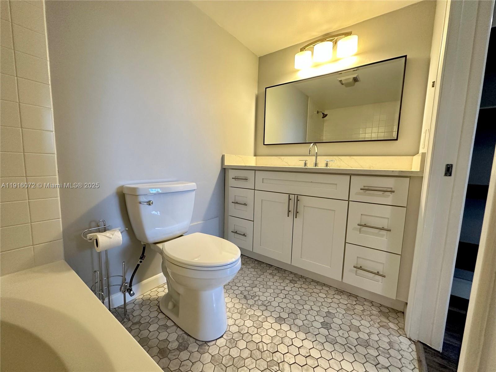 22970 Oxford Place, Unit A Boca Raton, FL 33433 - Photo 14 of 24 a bathroom with a toilet sink and mirror