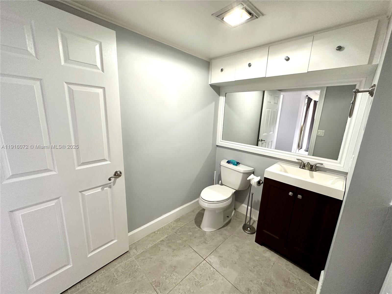 22970 Oxford Place, Unit A Boca Raton, FL 33433 - Photo 18 of 24 a bathroom with a toilet sink and mirror