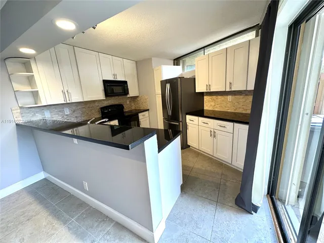 a kitchen with stainless steel appliances a refrigerator a sink a stove a microwave a counter space and cabinets