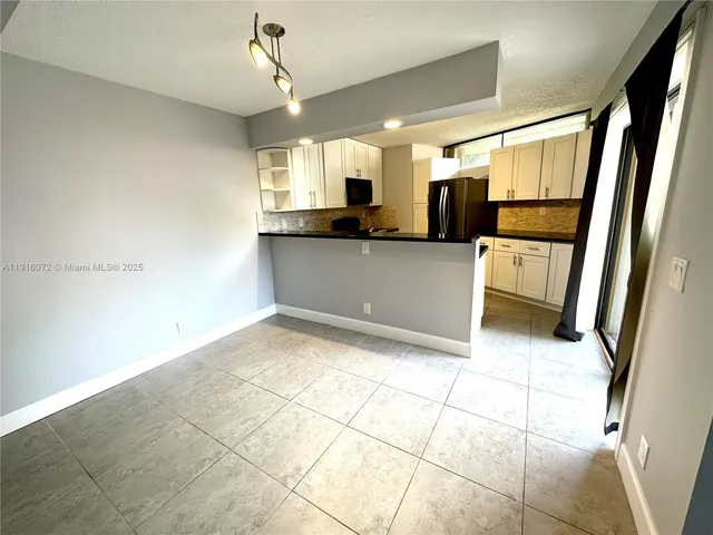 a view of a refrigerator in kitchen and an empty room