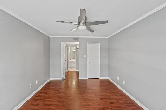 a view of empty room with wooden floor and ceiling fan