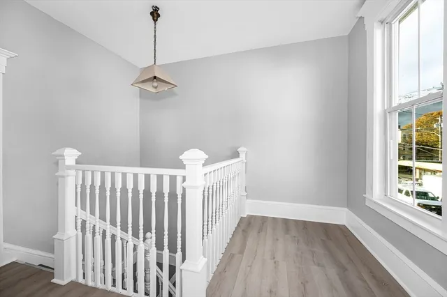 a view of hallway with window and wooden floor