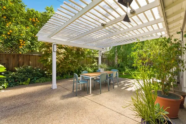 a view of a patio with table and chairs potted plants and large tree