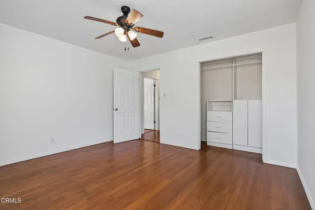 a view of empty room with wooden floor and ceiling fan
