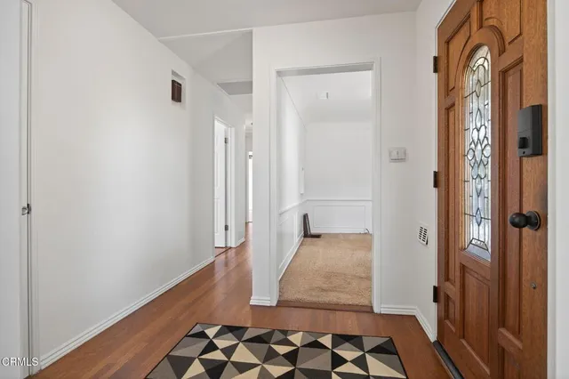 a view of a hallway with wooden floor and a bathroom
