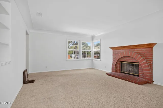 an empty room with windows & fireplace
