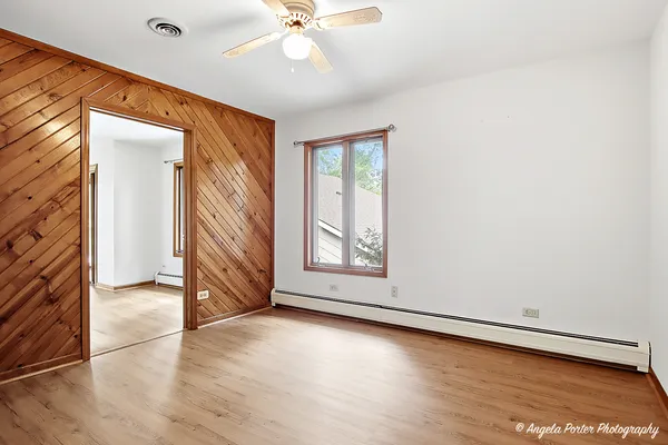 an empty room with wooden floor cabinet and windows