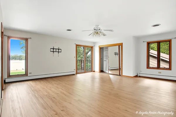 a view of an empty room with window and wooden floor