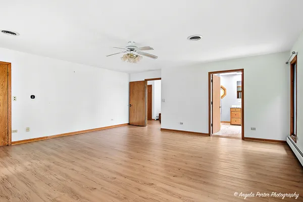 a view of an empty room with window and wooden floor