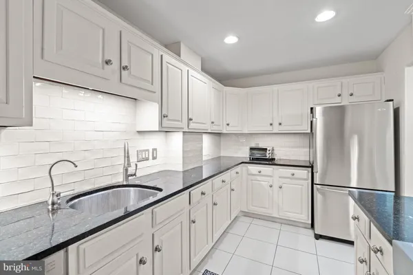 a kitchen with granite countertop white cabinets and white stainless steel appliances