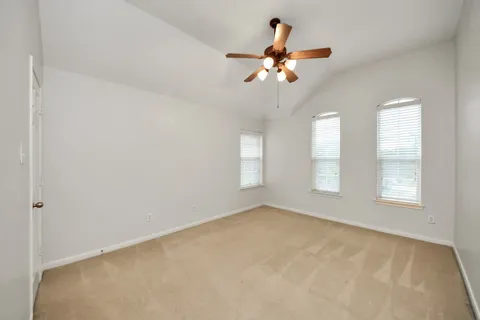 an empty room with windows and chandelier fan