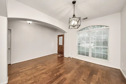 a view of an empty room with wooden floor and windows