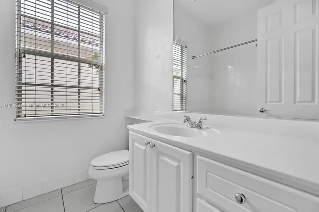 a bathroom with a granite countertop sink toilet a large mirror and a window