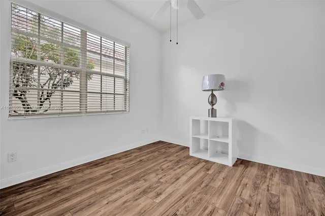 an empty room with wooden floor cabinet and windows