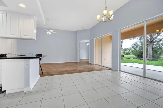 a view of a livingroom with a chandelier potted plants and wooden floor