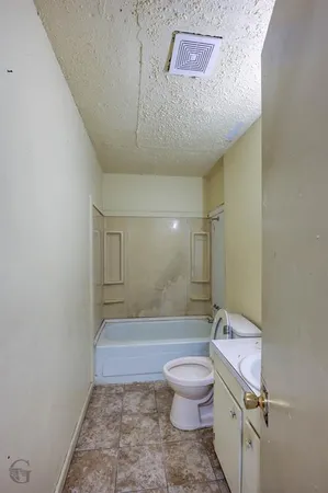 a bathroom with a granite countertop sink a toilet a mirror and bathtub