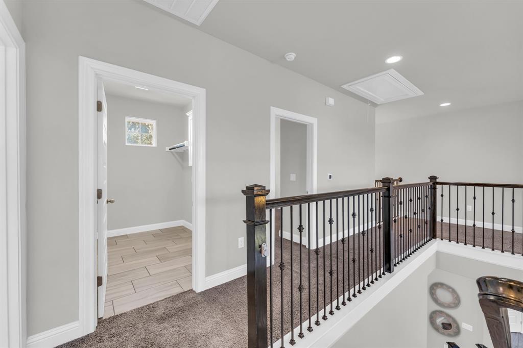 110 Magona Trail Georgetown, TX 78628 - Photo 22 of 38 A well-lit landing features wrought iron railings and neutral carpet, leading to a utility space with tiled flooring and a window.