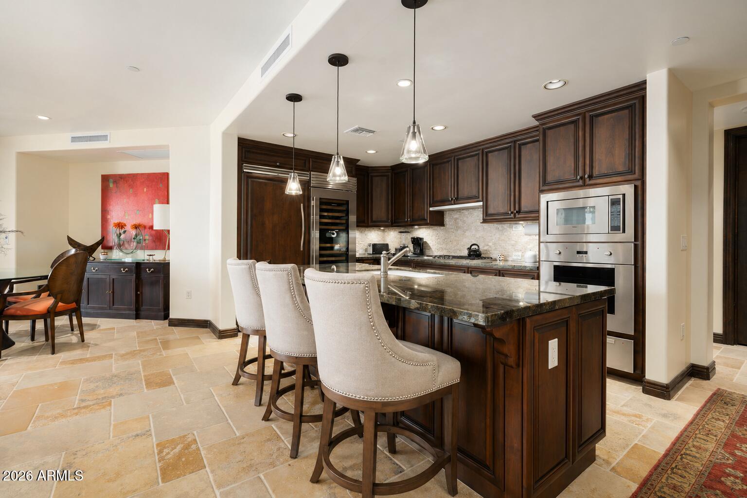 7181 East Camelback Road, Unit 1001 Scottsdale, AZ 85251 - Photo 5 of 34 a kitchen with stainless steel appliances granite countertop a kitchen island a stove a refrigerator a sink a dining table and chairs with wooden floor
