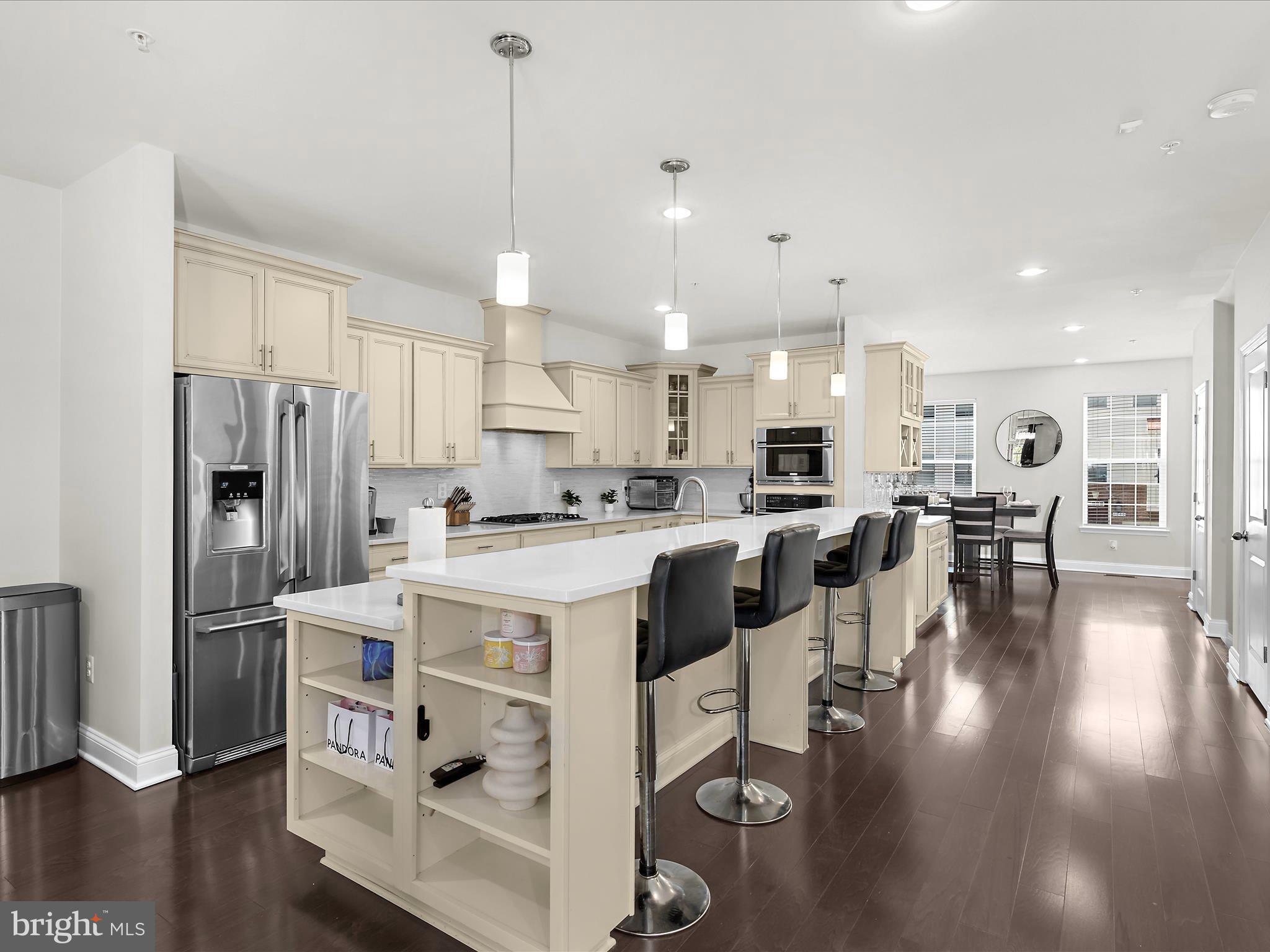 1239 Orchid Road Gambrills, MD 21054 - Photo 7 of 58 a kitchen with stainless steel appliances kitchen island granite countertop a refrigerator a stove top oven a sink and a dining table with wooden floor