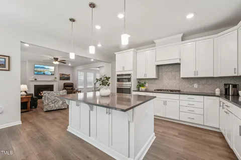 a kitchen with kitchen island granite countertop a sink cabinets and wooden floor