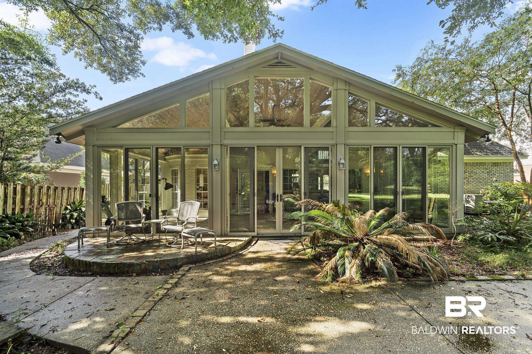Back of property featuring a sunroom, a patio, and brick siding