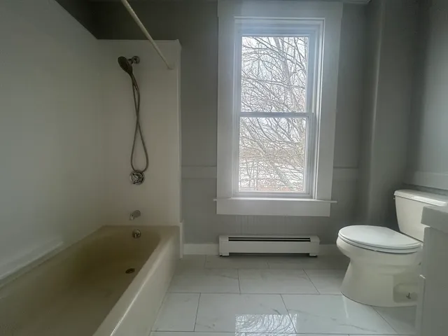 a bathroom with a tub toilet and window