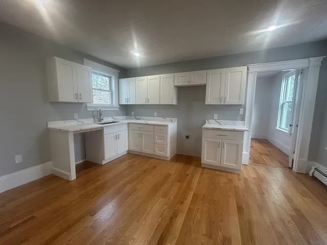 a kitchen with wooden floors and white cabinets