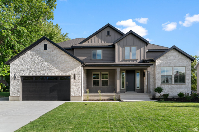 2724 Mt Jordan Road Sandy, UT 84092 - Photo 1 of 39 Modern farmhouse exterior featuring a stone and board-and-batten facade, a covered front porch, an attached two-car garage, and a concrete driveway
