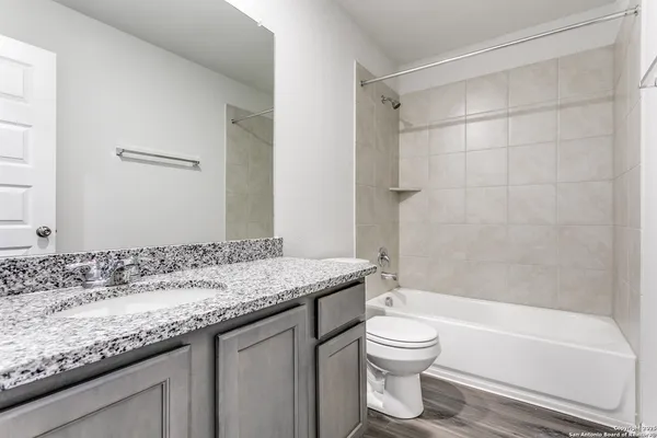 a bathroom with a granite countertop sink a toilet and bathtub