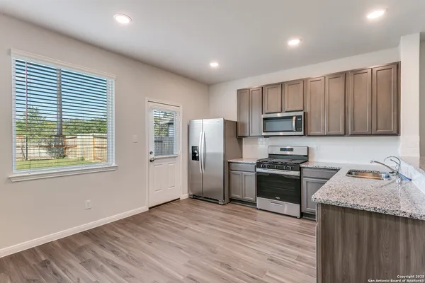 a kitchen with kitchen island granite countertop stainless steel appliances cabinets a sink and a window