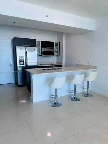 a living room with stainless steel appliances kitchen island granite countertop a sink and a stove top oven