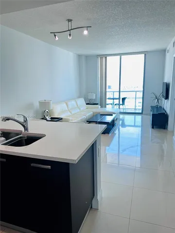 a kitchen with a sink a counter top space and living room filled with furniture