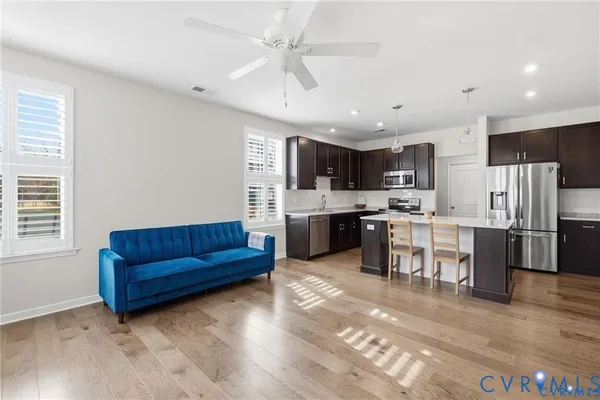 a living room with stainless steel appliances kitchen island granite countertop a stove a refrigerator a oven a sink with a dining table and chairs