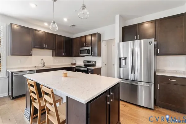 a kitchen with kitchen island a counter space a sink appliances and cabinets