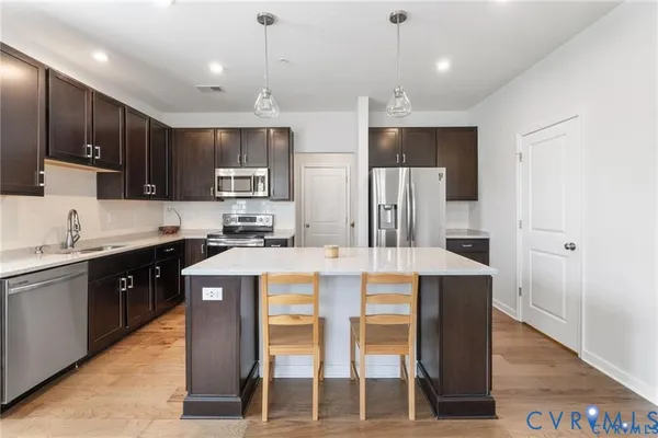 a kitchen with kitchen island granite countertop wooden cabinets and refrigerator