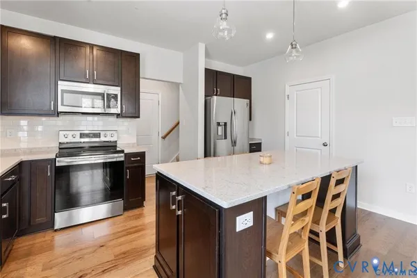 a kitchen with stainless steel appliances kitchen island granite countertop a stove a sink and a refrigerator