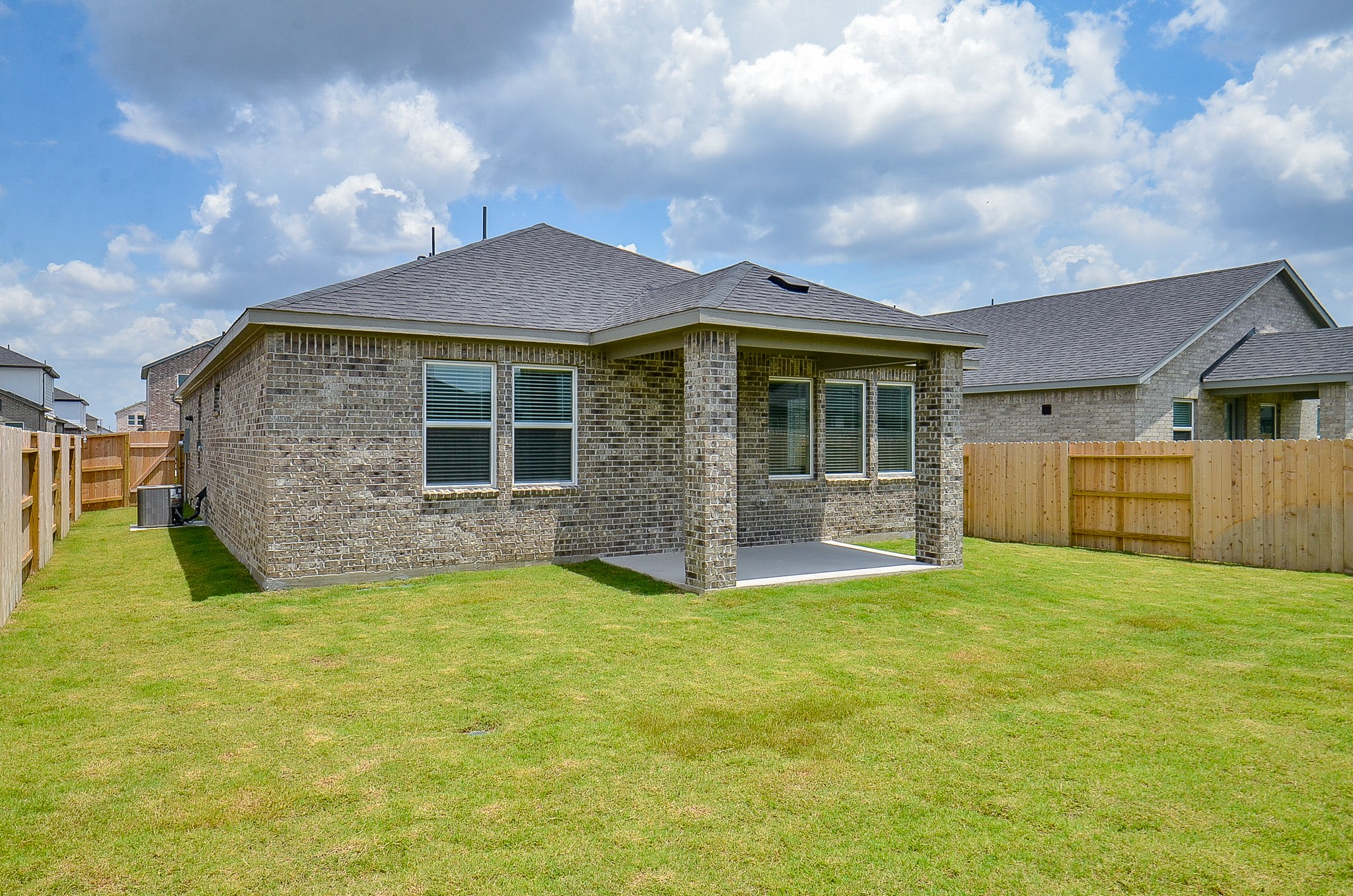 9727 Rialto Hts Drive Cypress, TX 77433 - Photo 37 of 37 This photo showcases the backyard of a single-story brick home featuring a covered patio and a spacious, fenced-in grassy area, ideal for outdoor activities.
