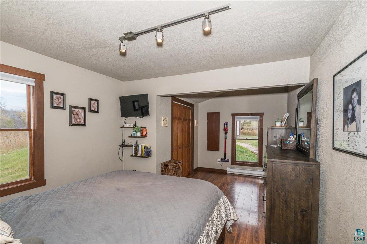 7702 East Rockmont Road Poplar, WI 54864 - Photo 11 of 22 Bedroom featuring a textured ceiling, track lighting, a baseboard heating unit, and dark hardwood / wood-style floors