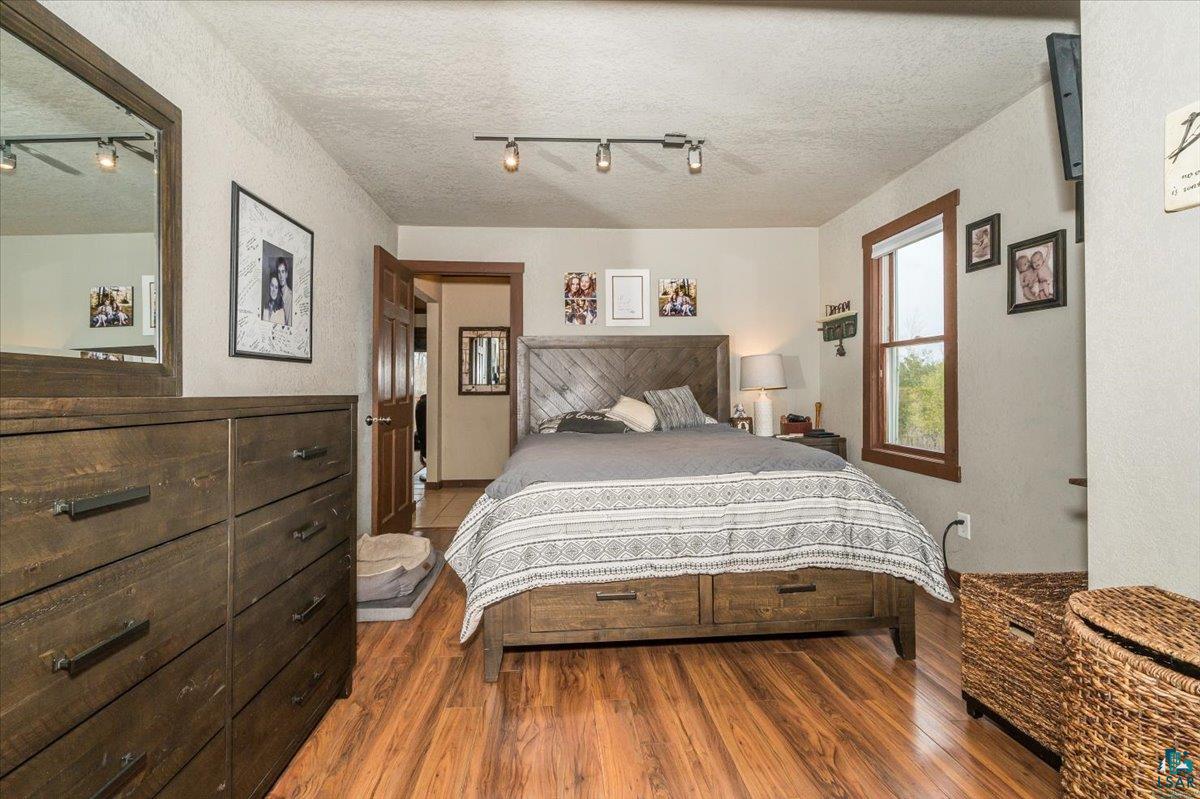 7702 East Rockmont Road Poplar, WI 54864 - Photo 12 of 22 Bedroom with dark hardwood / wood-style floors, a textured ceiling, and rail lighting
