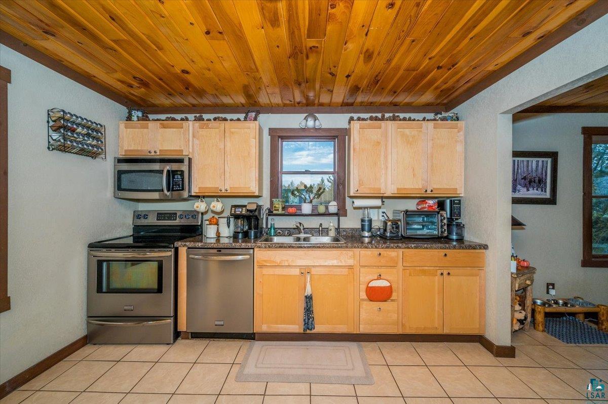7702 East Rockmont Road Poplar, WI 54864 - Photo 7 of 22 Kitchen with light brown cabinetry, sink, stainless steel appliances, and light tile patterned floors