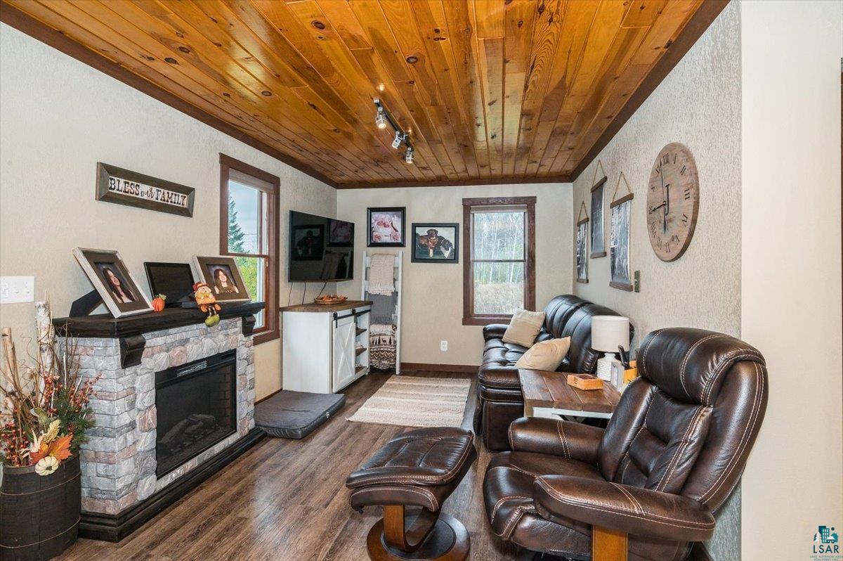 7702 East Rockmont Road Poplar, WI 54864 - Photo 10 of 22 Living room featuring track lighting, wooden ceiling, ornamental molding, a fireplace, and dark hardwood / wood-style flooring