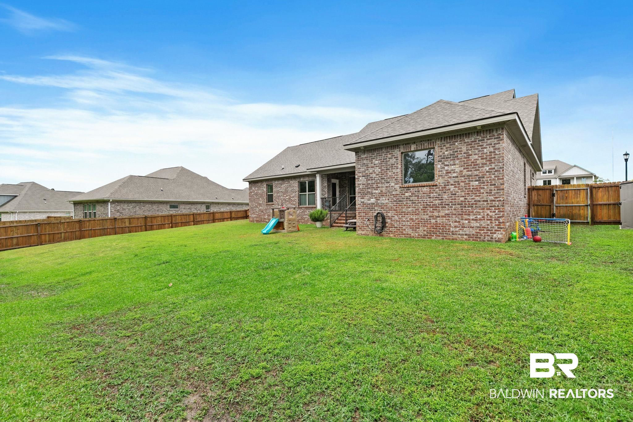 13233 Ibis Boulevard Daphne, AL 36527 - Photo 64 of 100 Expansive green lawn with a wood privacy fence bordering the property