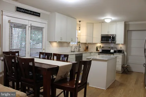a kitchen with granite countertop a dining table chairs and a refrigerator