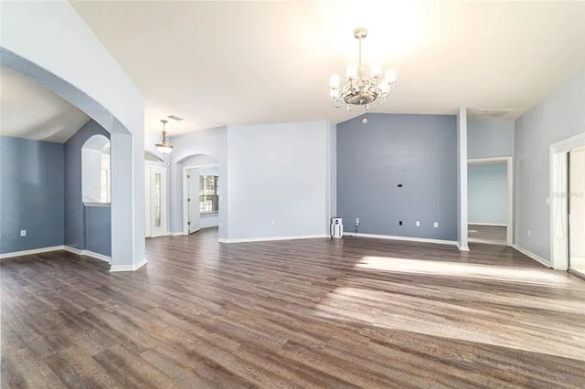 a view of empty room with wooden floor and chandelier