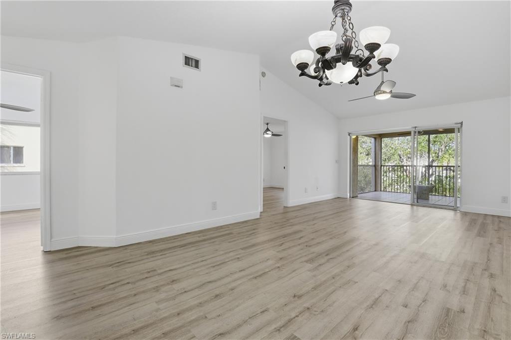 7762 Jewel Lane, Unit 201 Naples, FL 34109 - Photo 13 of 39 a view of a room with wooden floor and chandelier
