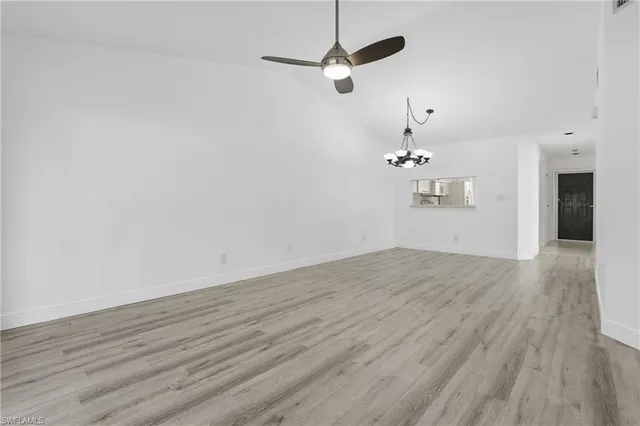 an empty room with wooden floor ceiling fan and window