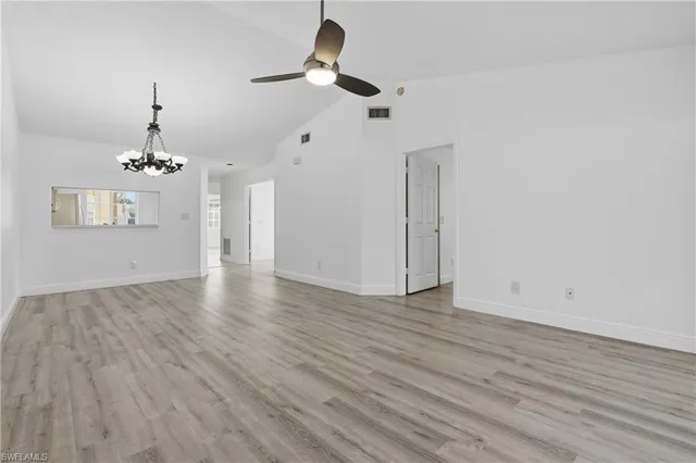 wooden floor in an empty room with a chandelier fan