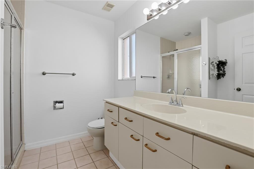 7762 Jewel Lane, Unit 201 Naples, FL 34109 - Photo 21 of 39 a bathroom with a granite countertop sink a toilet and a mirror