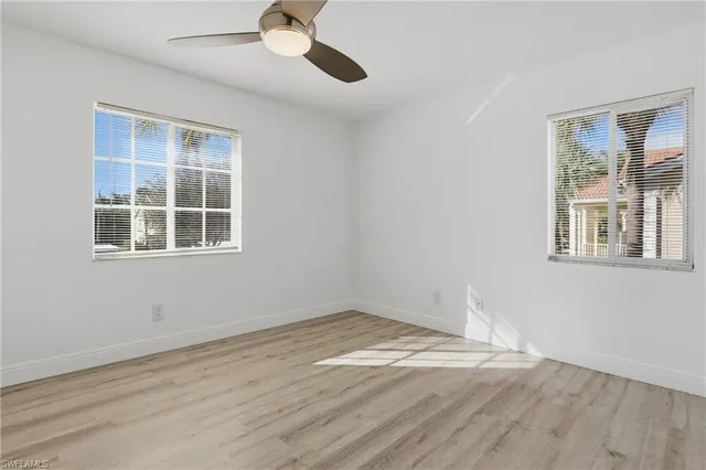 a view of empty room with wooden floor and fan