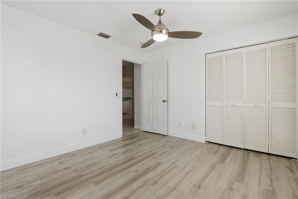 7762 Jewel Lane, Unit 201 Naples, FL 34109 - Photo 24 of 39 an empty room with wooden floor ceiling fan and windows